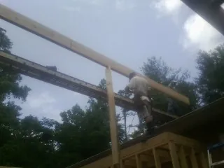 Carpenter setting a ridge beam over a new addition frame — Ice Dam Removal by Roofing Brothers in Cecilia