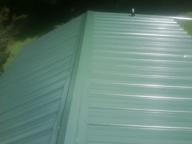 New green metal panels meeting at the ridge of a roof in Cecilia