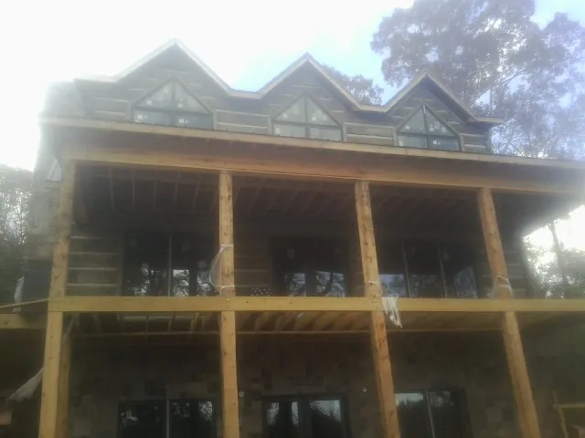 Dormers and porch framing on a large log home under construction — Roof Coating work by our crew in Cecilia