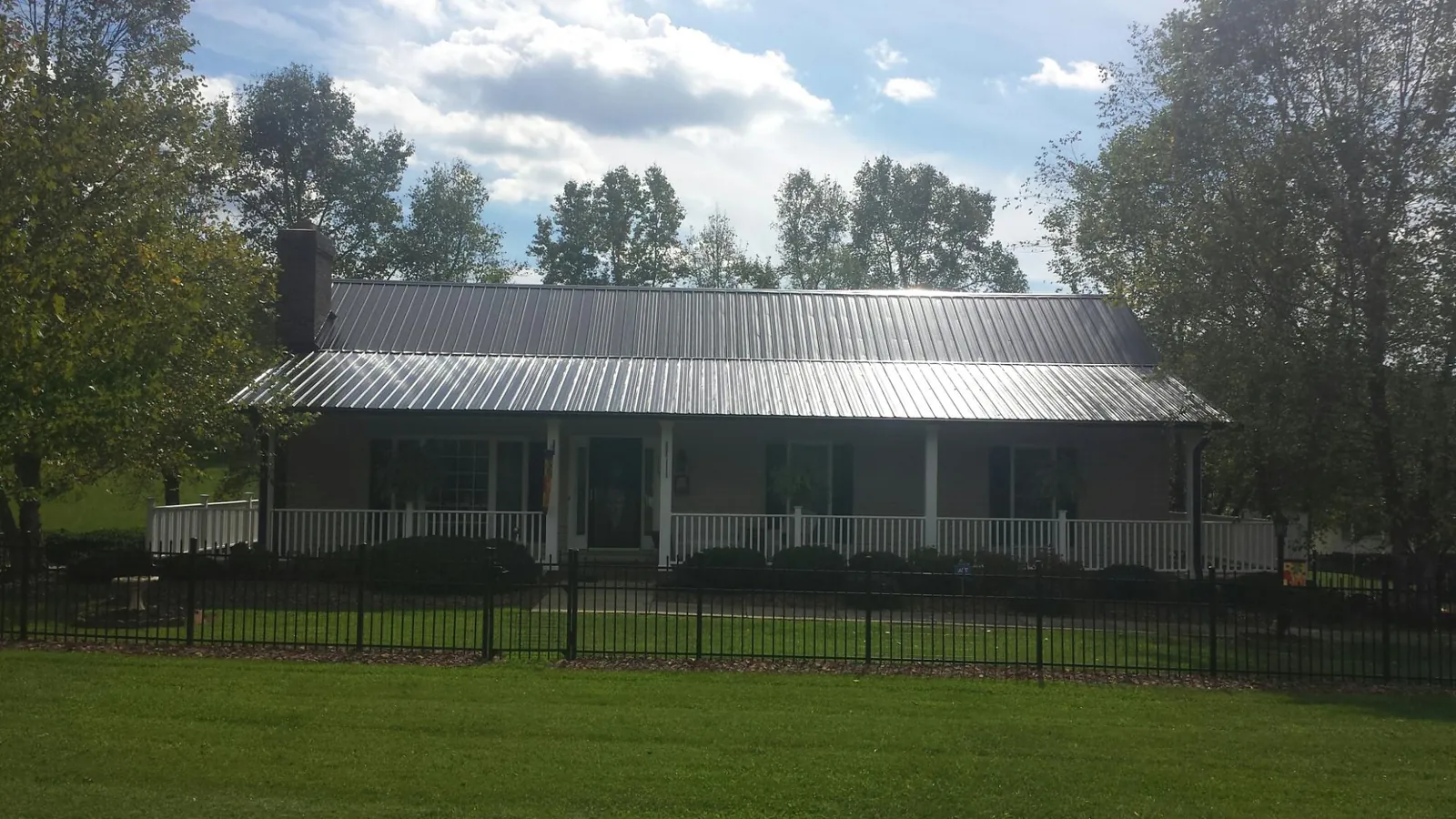 Gray metal roof on a brick ranch with a full width front porch — Gutter Guard Installation work by our crew in Cecilia