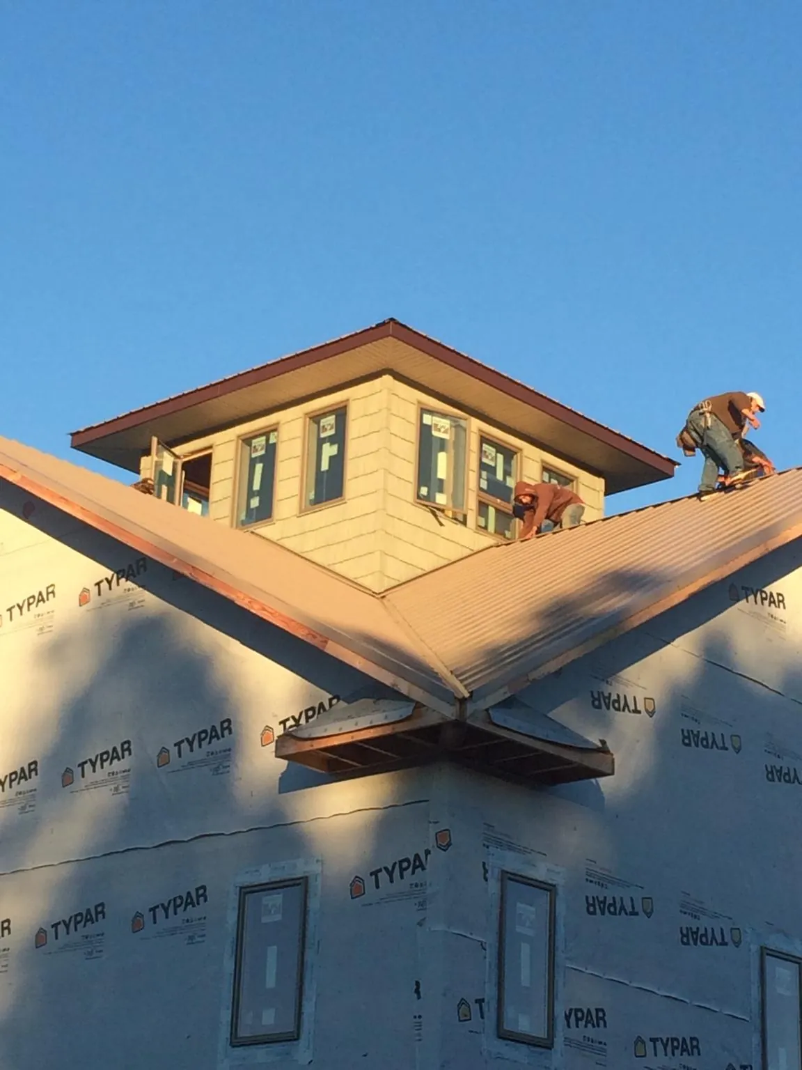 Roofers working around a rooftop cupola on a new metal roof at sunset — Roof Waterproofing in Cecilia by Roofing Brothers